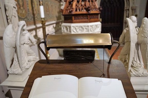 Liturgischer Tisch mit einem offenen Buch und Kerzenständer im Hintergrund.