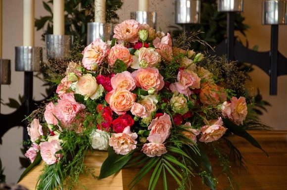 Bunte Blumenarrangements mit Rosen und Pflanzen, dekoriert mit Kerzen.